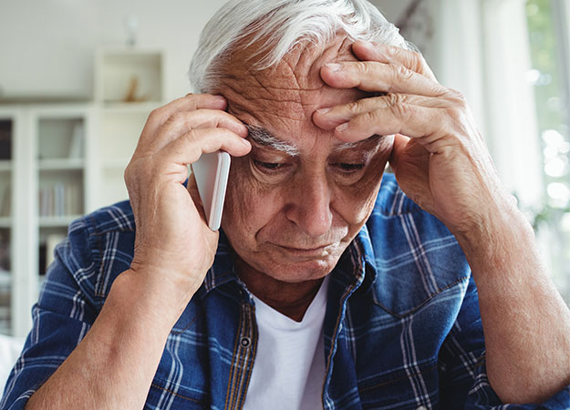 Afbeelding van man die telefoneert terwijl hij zijn hoofd vasthoudt