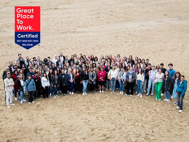 Audika-team viert Great Place to Work-certificering 2022-2023 op het strand in België.